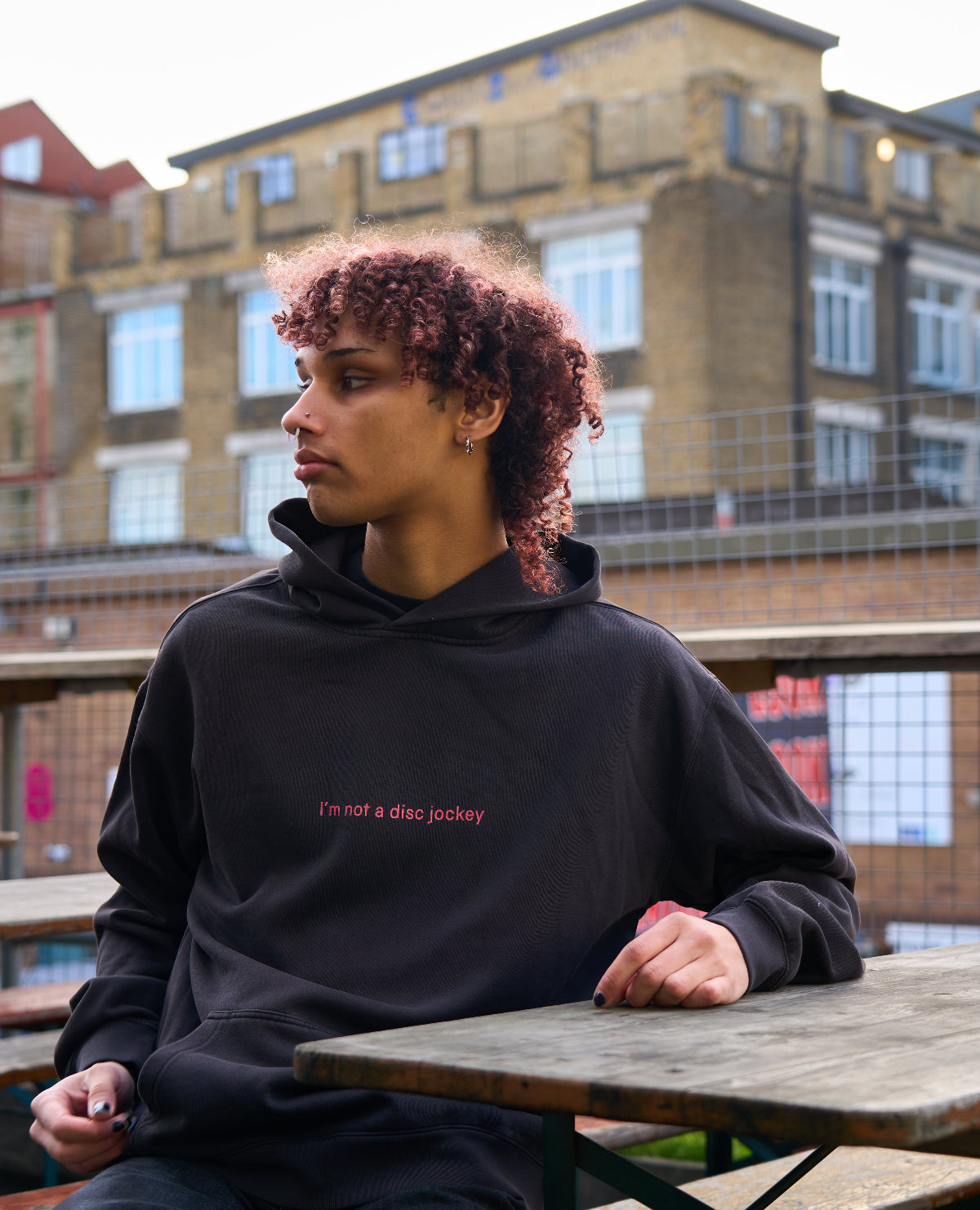Model in I'M NOT A DJ Hoodie - Hun Sauce, Black hood for DJs. I'm not disc jockey collection for the rave. Heavyweight hood. Now available at the record store at All My Friends, in Hackney.