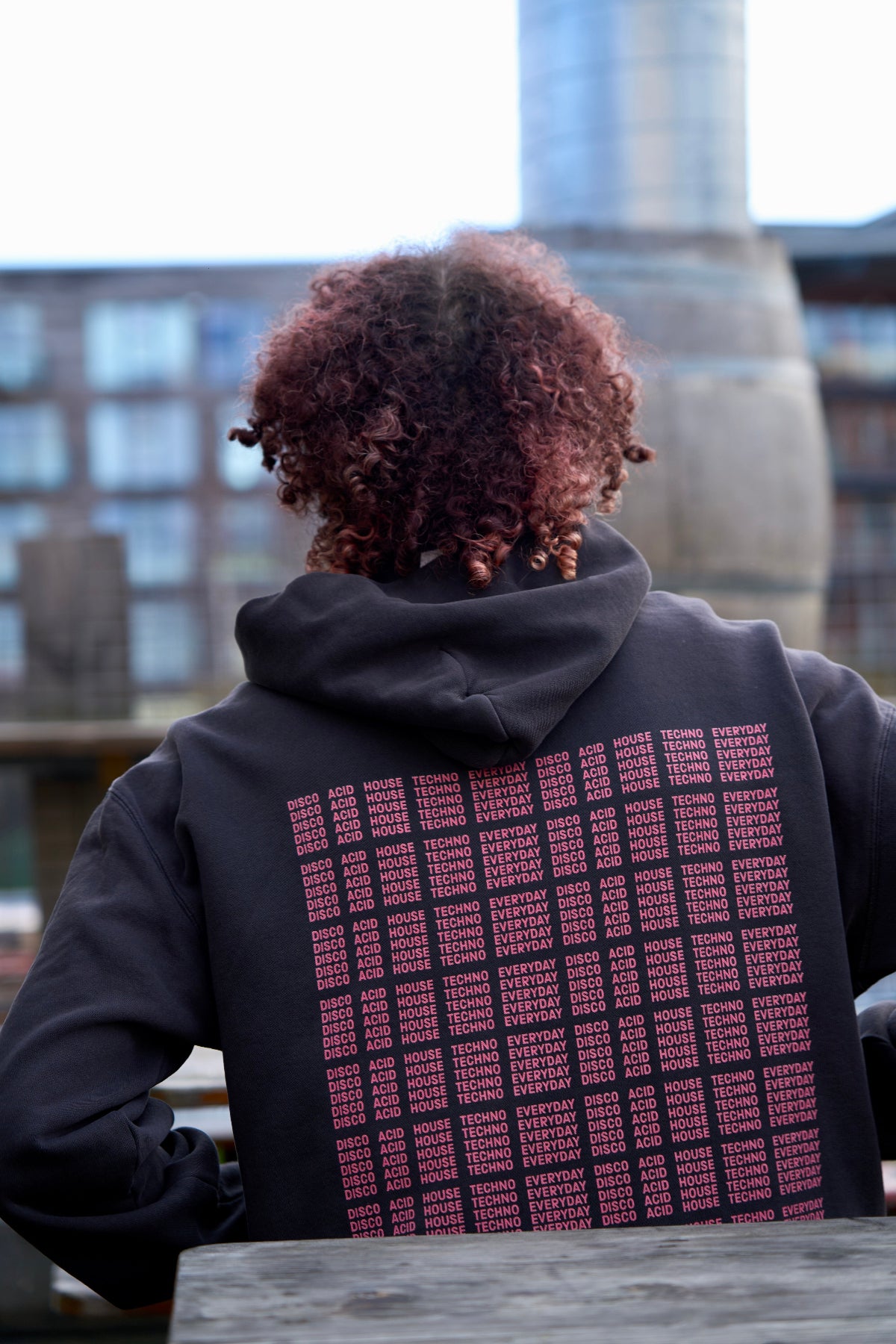 Model in I'M NOT A DJ Hoodie - Hun Sauce, Black hood for DJs. I'm not disc jockey collection for the rave. Heavyweight hood. Now available at the record store at All My Friends, in Hackney.